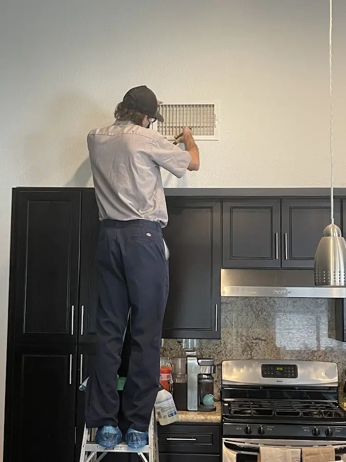 Technician inspecting an air vent during HVAC service in Sterling Heights